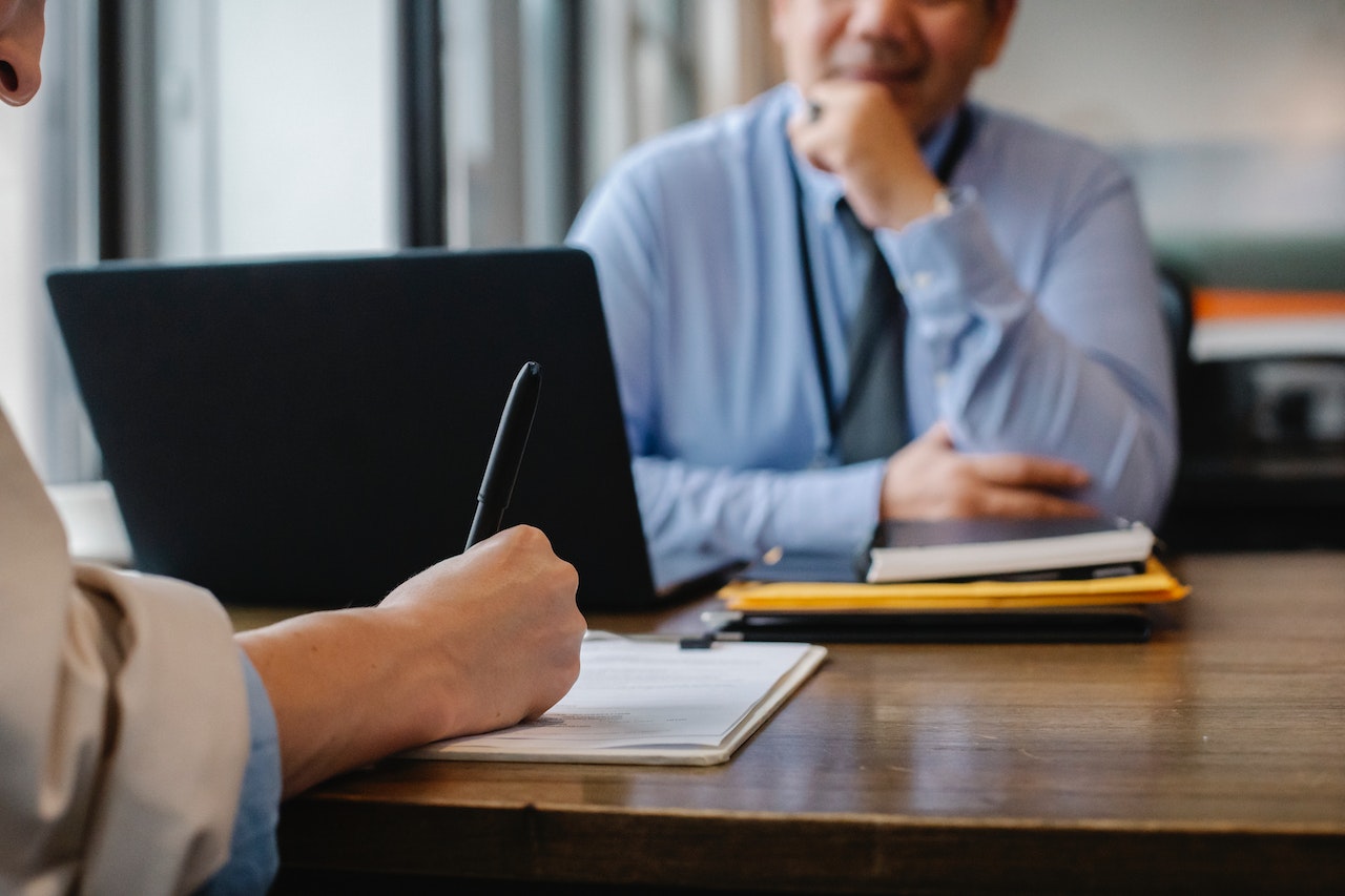 Close-up-of-hand-holding-pen-writing-something-on-interview-interview-coaching
