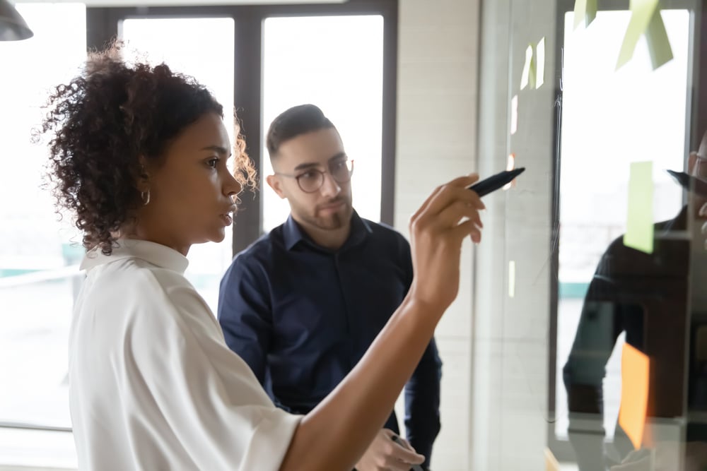 Focused-multiracial-employees-write-ideas-on-glass-wall-why-do-we-fear-failure