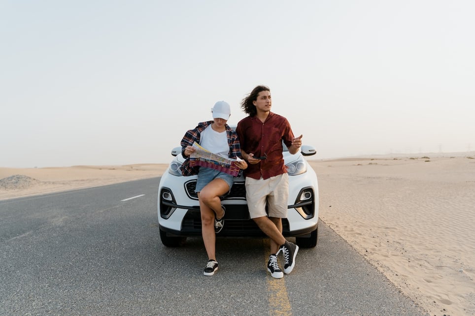 Man-and-woman-in-the-middle-of-the-road-looking-at-map-leaning-on-car-why-take-a-gap-year