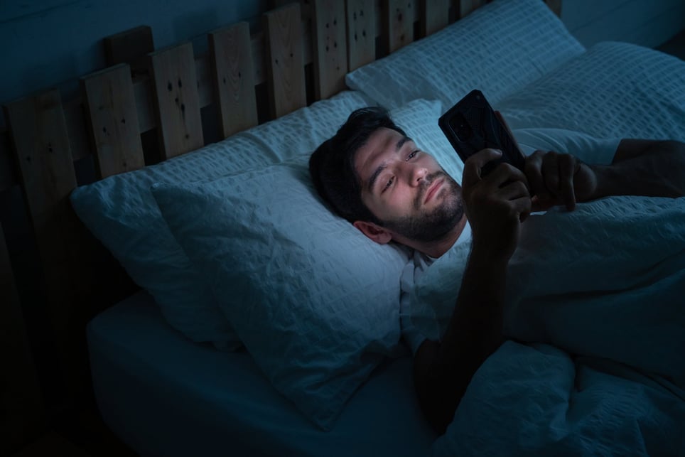 Man-using-his-phone-in-bed-late-at-night-revenge-bedtime-procrastination