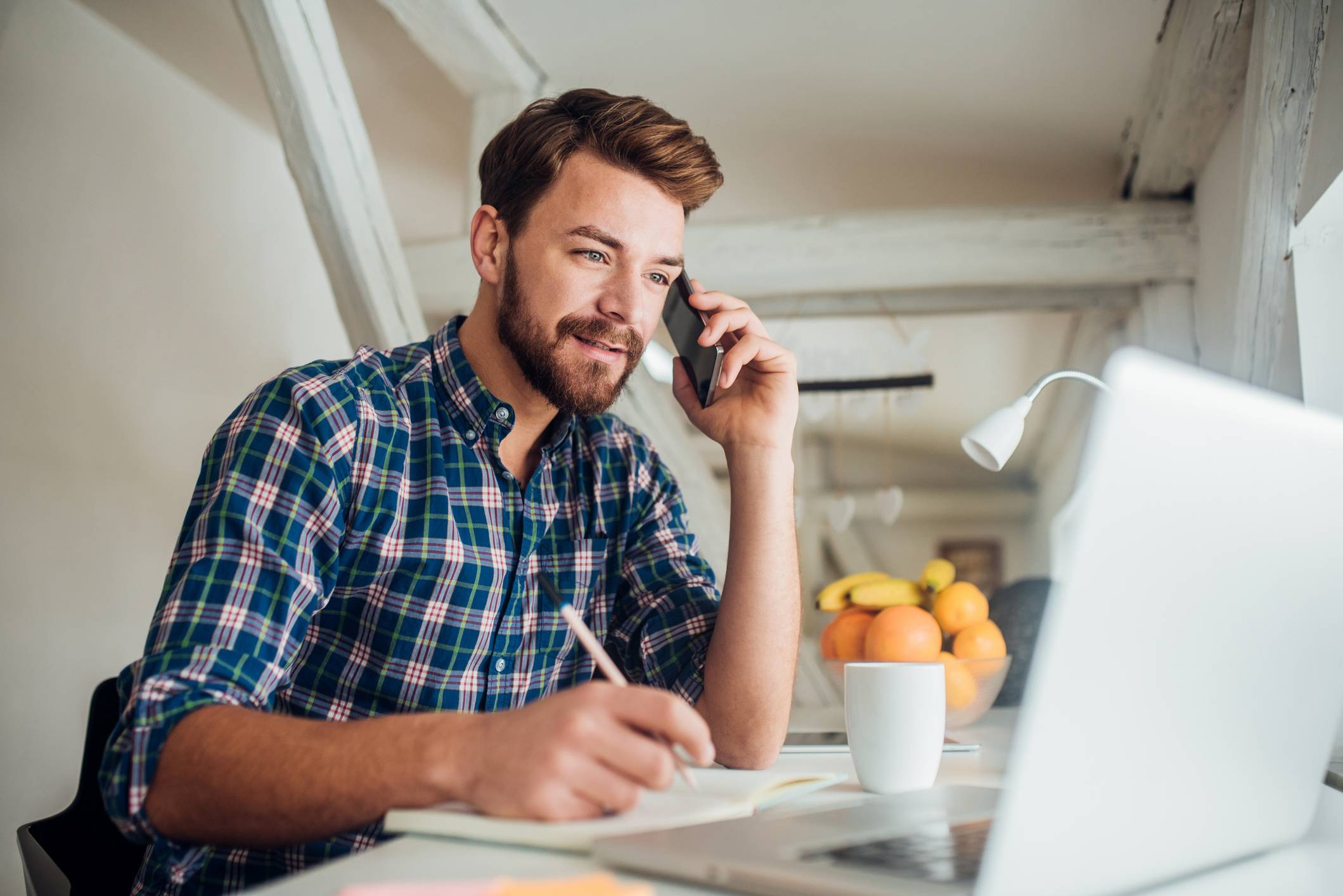 Man-writing-and-talking-on-phone-why-are-you-looking-for-a-new-job
