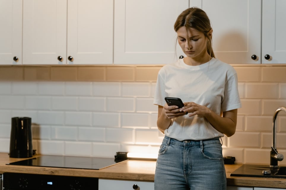 Sad-woman-on-her-phone-standing-alone-in-her-kitchen-how-to-handle-homesickness