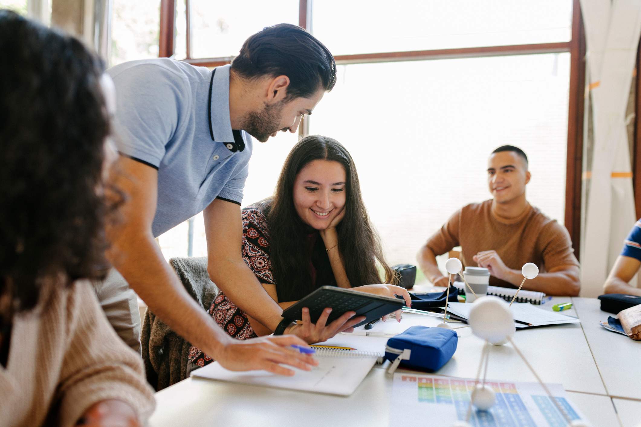 Teen-girl-smiling-looking-at-project-with-teacher-at-classroom-how-emotions-affect-learning