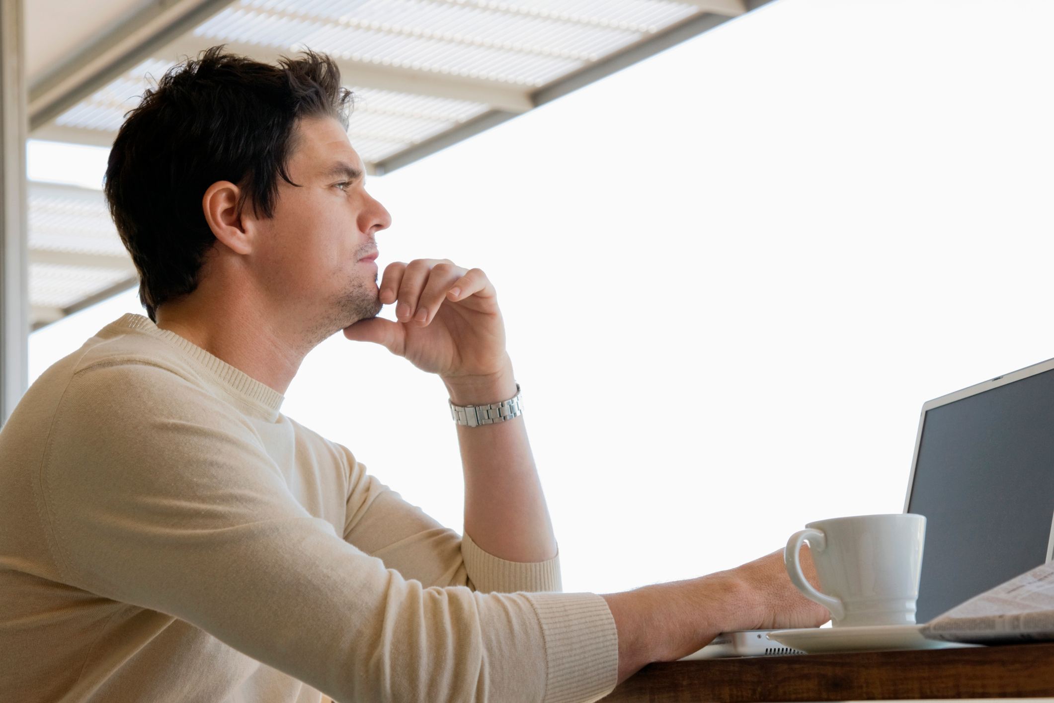 Thoughtful-man-looking-outside-in-front-of-laptop-worried-about-getting-fired