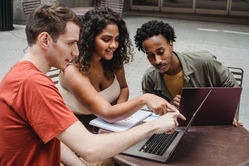 Three-friends-looking-and-pointing-at-laptop-personal-brand-statement