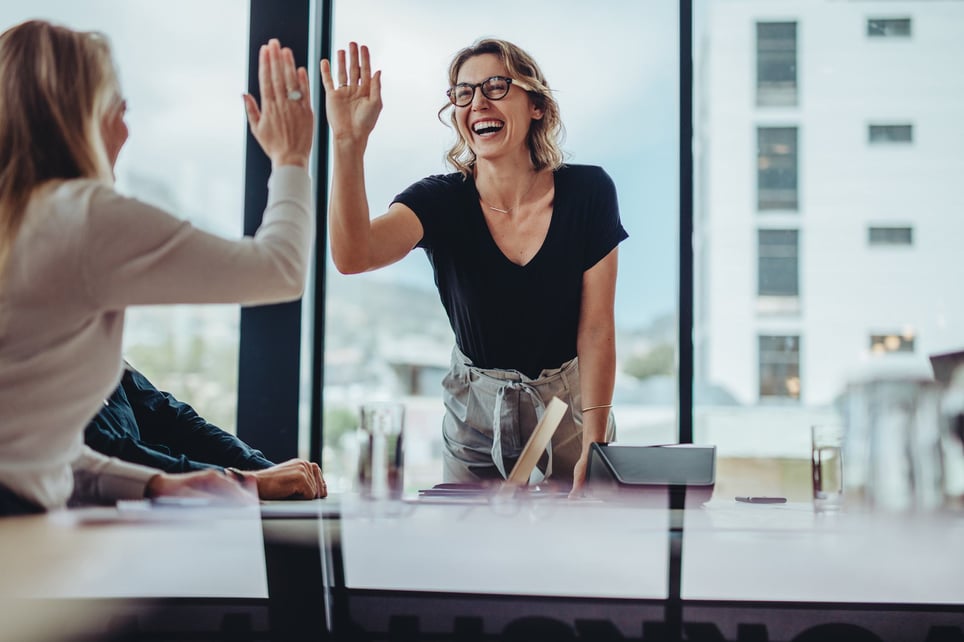 Two-collegues-at-office-smiling-and-giving-high-five-teamwork-skills
