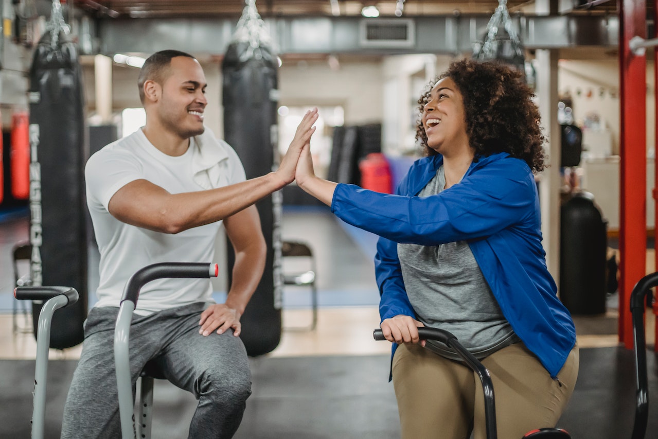 Woman-giving-high-five-to-fitness-coach-while-doing-cardio-work-out-fitness-goals