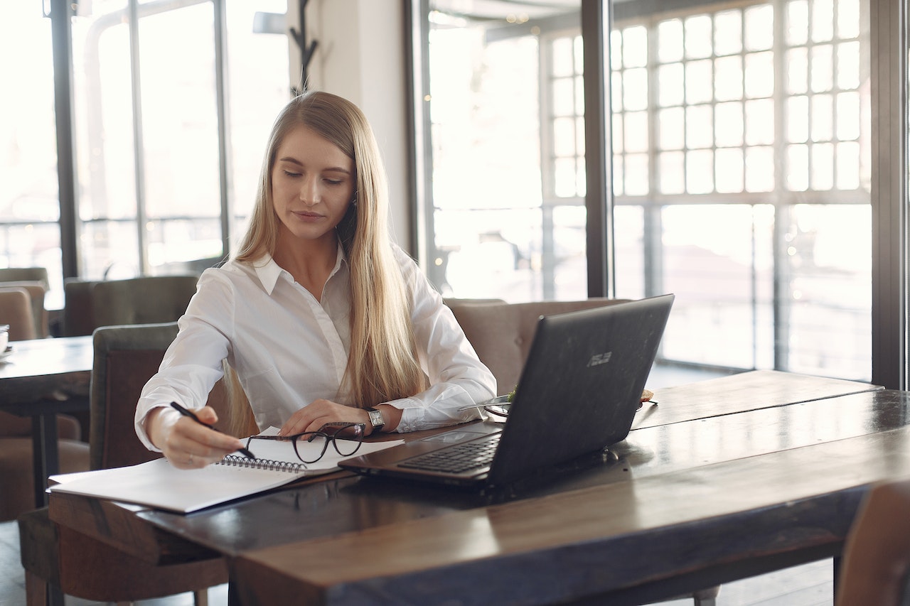 Woman-working-on-laptop-thinking-and-writing-on-notebook-decision-making-skills