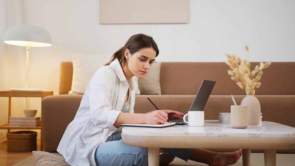 Young-woman-using-laptop-and-taking-notes-thank-you-letter-after-interview