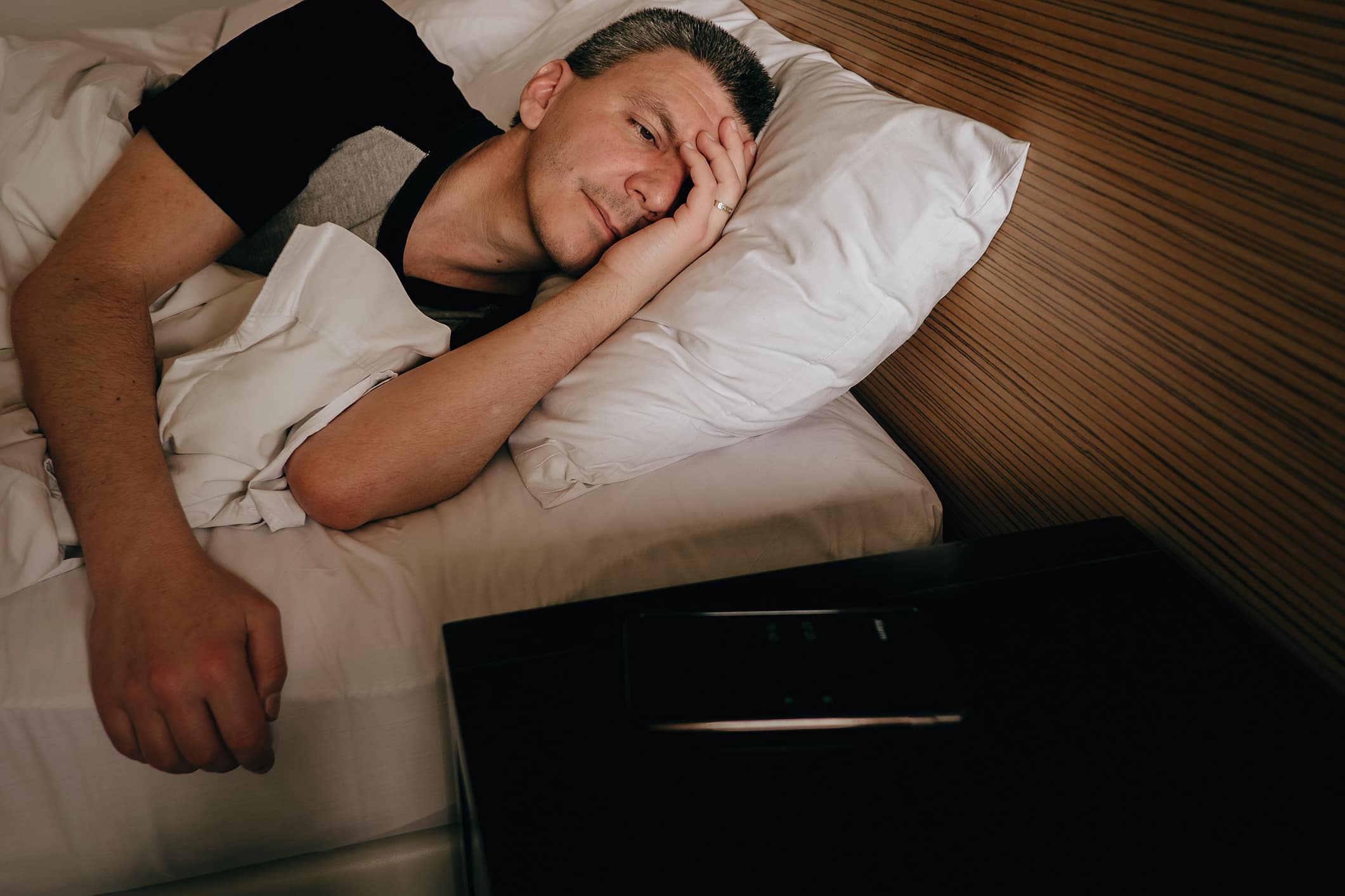 man-in-bed-looking-at-cell-phone-alarm-progressive-muscle-relaxation-techniques