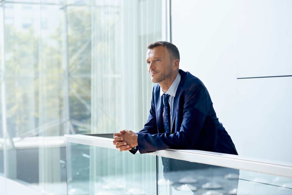smiling-businessman-leaning-on-railing-millionaire-mindset