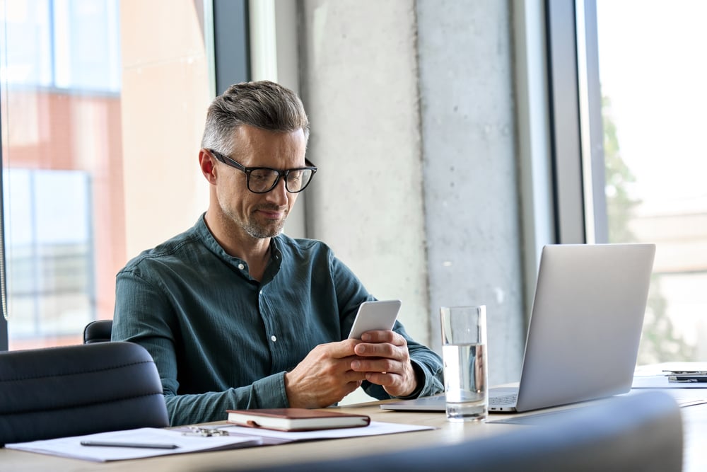 smiling-mature-businessman-holding-smartphone-how-to-avoid-distractions