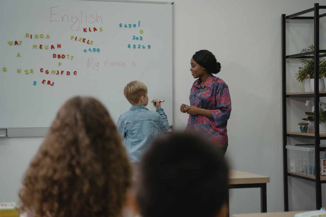 woman-teacher-at-class-teaching-little-kid-at-whiteboard-maslows-hierarchy-of-needs